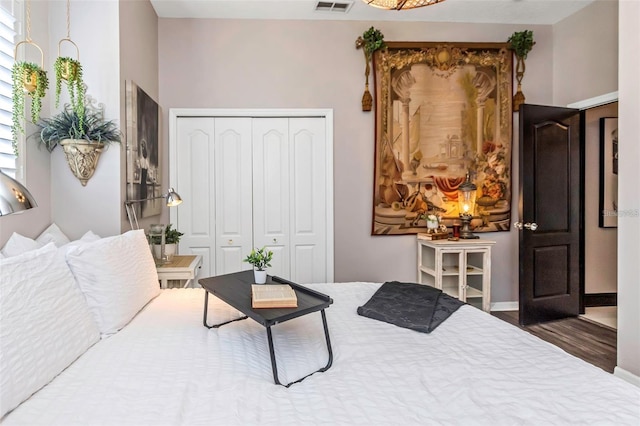 bedroom featuring a closet, wood finished floors, visible vents, and baseboards