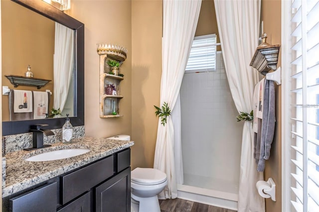 bathroom with a stall shower, vanity, toilet, and wood finished floors