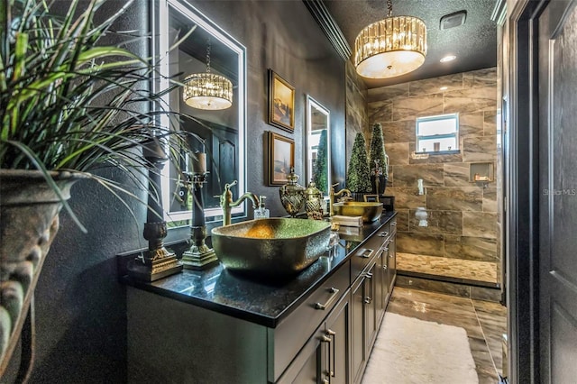 bathroom featuring double vanity, a sink, a textured ceiling, and a walk in shower