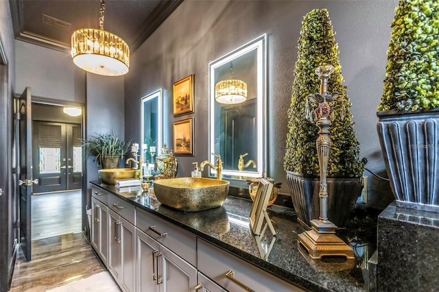 bathroom featuring crown molding, double vanity, a sink, and wood finished floors