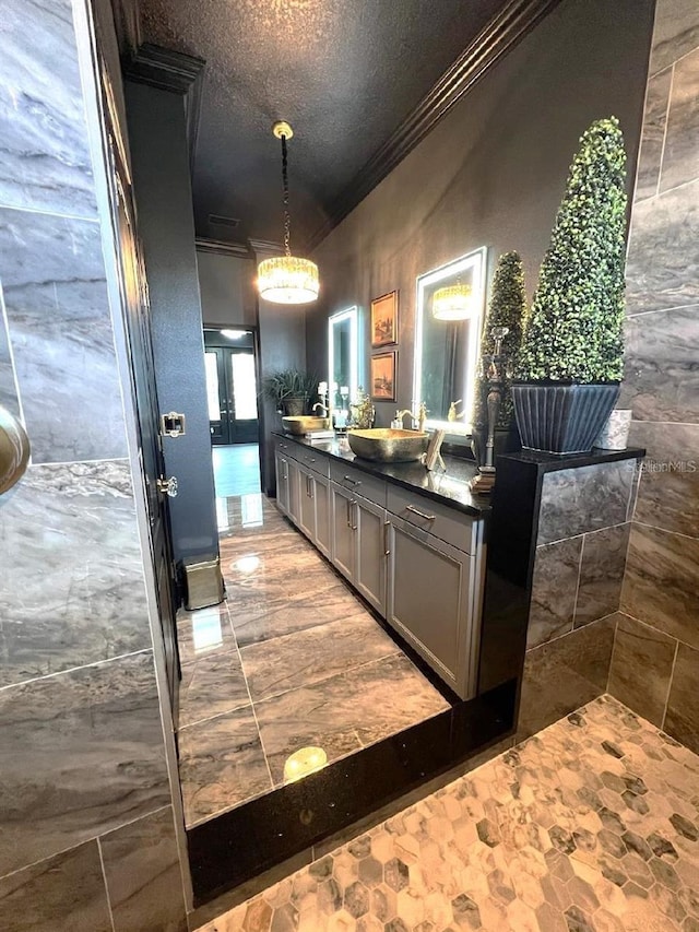 bar with a sink, ornamental molding, a textured ceiling, and decorative light fixtures