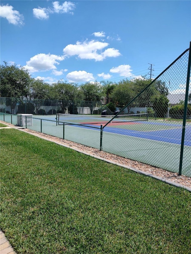 view of sport court featuring fence and a yard