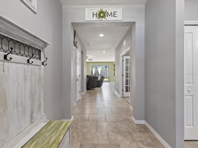 hall featuring baseboards and light tile patterned floors