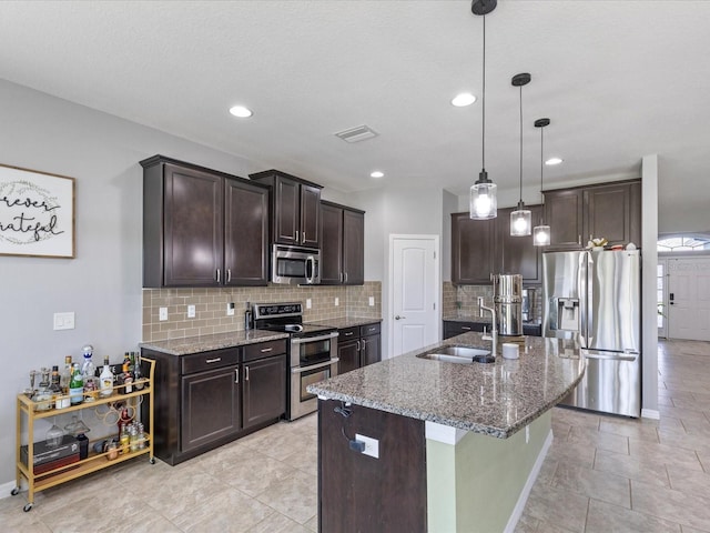 kitchen featuring dark brown cabinetry, stone counters, appliances with stainless steel finishes, and a sink