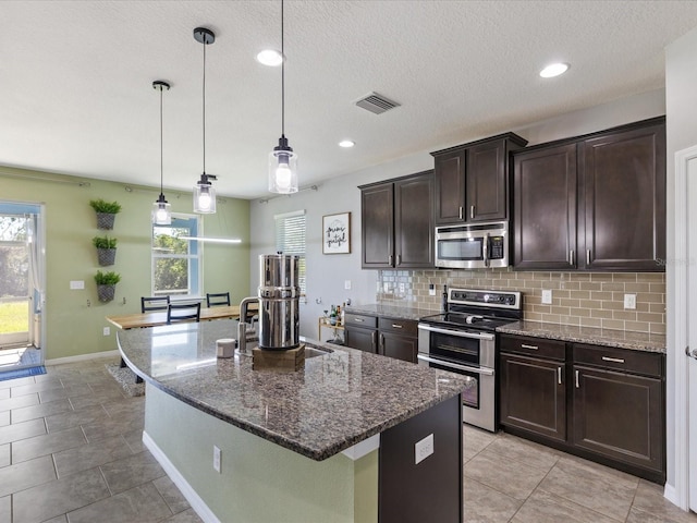 kitchen with dark brown cabinetry, visible vents, decorative backsplash, stainless steel appliances, and a sink