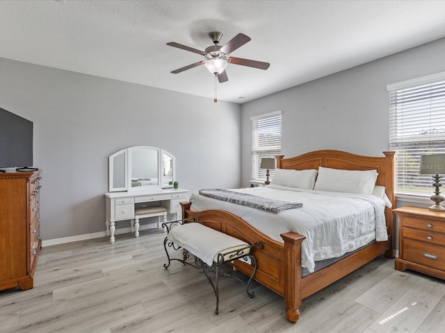 bedroom featuring ceiling fan, a textured ceiling, light wood-style flooring, and baseboards