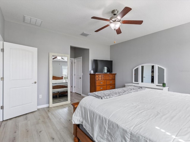 bedroom featuring baseboards, visible vents, ceiling fan, and light wood finished floors