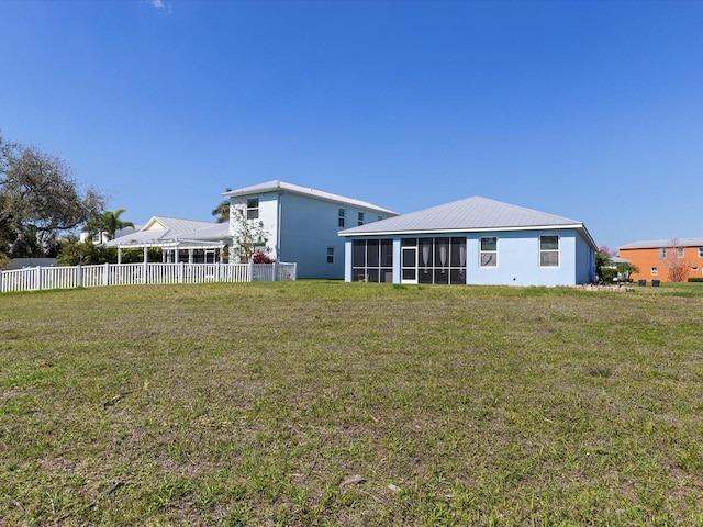 rear view of house with a sunroom, a yard, and fence