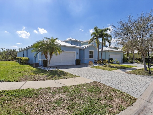 ranch-style house with a front lawn, decorative driveway, an attached garage, and stucco siding