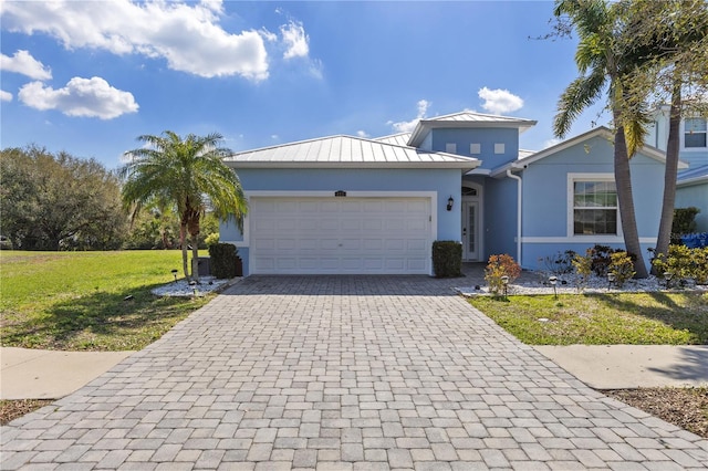 view of front of property with decorative driveway, stucco siding, an attached garage, a standing seam roof, and metal roof