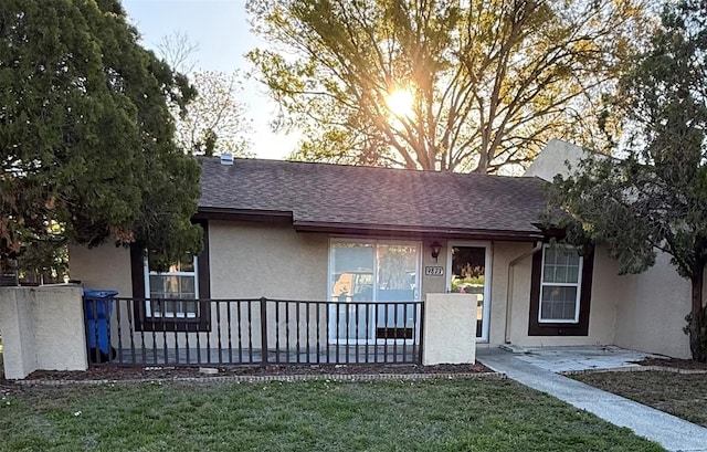 single story home with stucco siding, a front yard, and a shingled roof