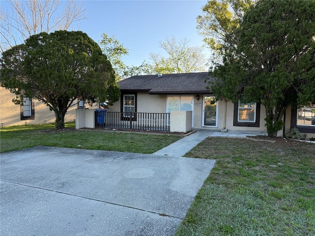 view of front of property featuring a front lawn, roof with shingles, and stucco siding