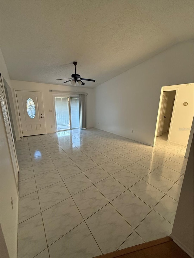 empty room with a wealth of natural light, lofted ceiling, a textured ceiling, and ceiling fan