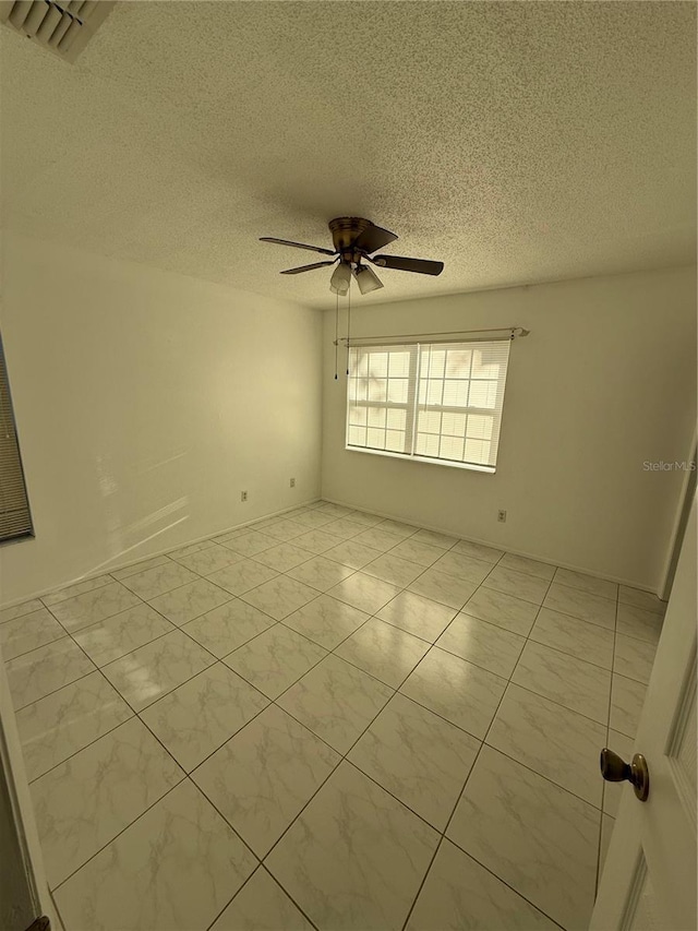 spare room with light tile patterned floors, visible vents, a textured ceiling, and ceiling fan