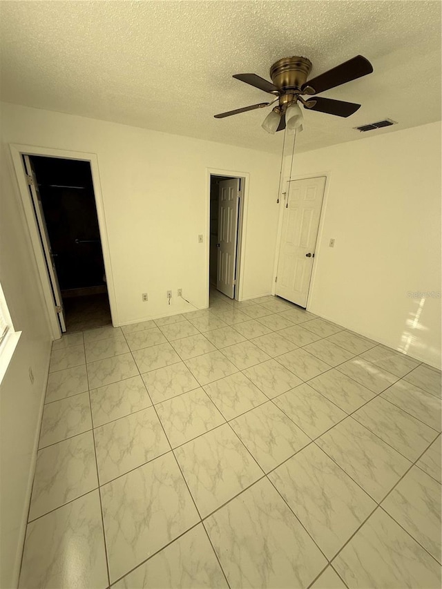 unfurnished room featuring visible vents, a textured ceiling, and a ceiling fan