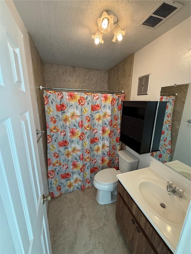 bathroom featuring visible vents, toilet, vanity, and a textured ceiling