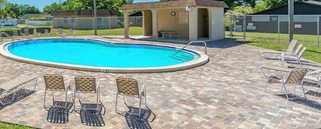 community pool featuring an outdoor structure, a patio, and fence