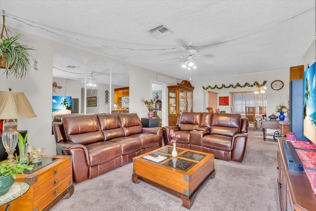 carpeted living area with visible vents, ceiling fan, and a textured ceiling