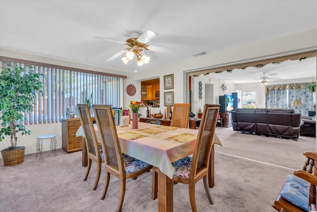 dining room with light carpet, ceiling fan, and visible vents