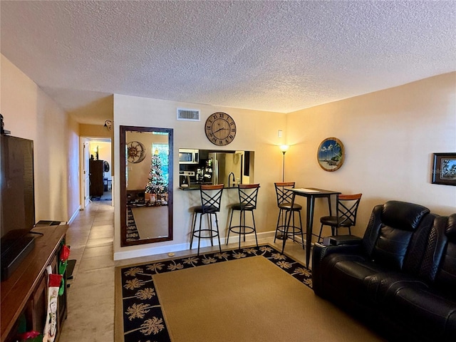 living area featuring visible vents, a textured ceiling, and baseboards