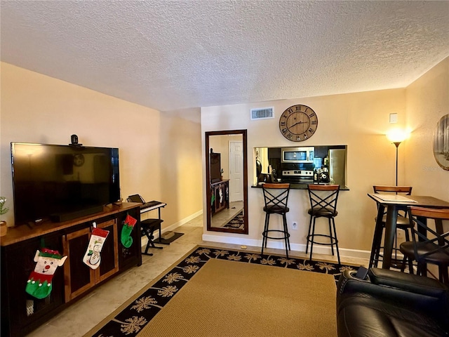 living area featuring baseboards, visible vents, and a textured ceiling