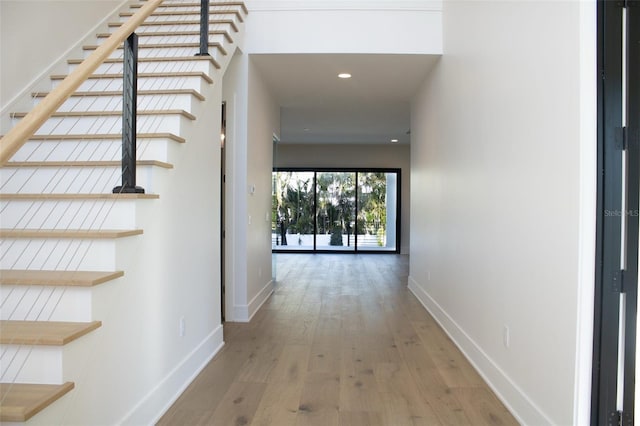 hall featuring light wood-type flooring, stairs, baseboards, and recessed lighting