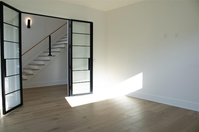 unfurnished room with stairs, baseboards, and wood finished floors