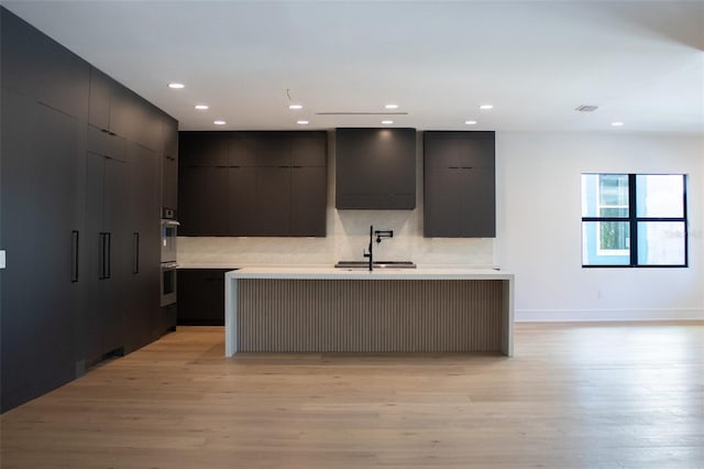 kitchen featuring light countertops, modern cabinets, a sink, and light wood-style flooring