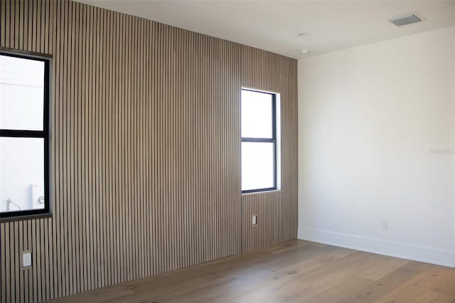 empty room featuring wood finished floors, visible vents, and baseboards