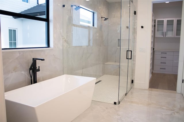 full bathroom with marble finish floor, a shower stall, and a freestanding bath