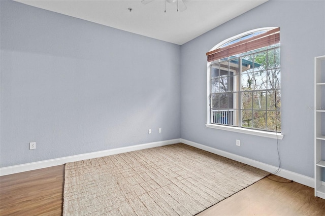 spare room with a ceiling fan, baseboards, and wood finished floors