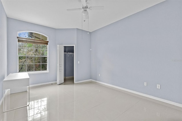 tiled empty room with a ceiling fan and baseboards