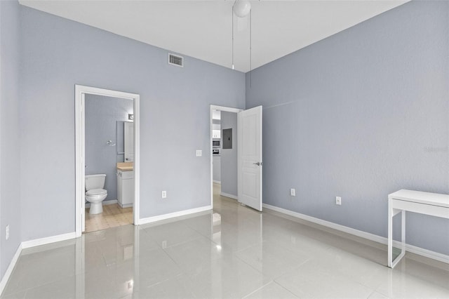 unfurnished bedroom featuring electric panel, baseboards, visible vents, ensuite bathroom, and tile patterned floors