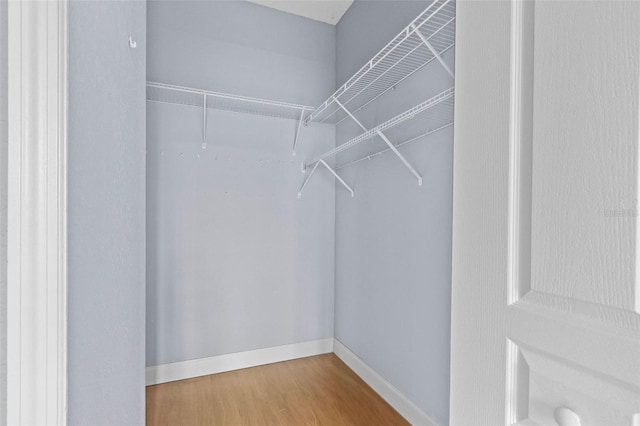 walk in closet featuring wood finished floors and attic access