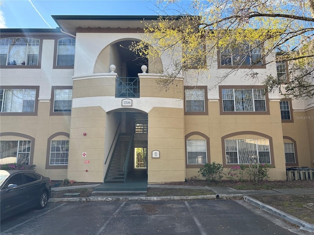 view of building exterior with uncovered parking and stairway