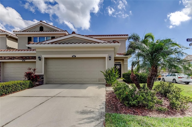 mediterranean / spanish-style house with a garage, driveway, a tiled roof, and stucco siding