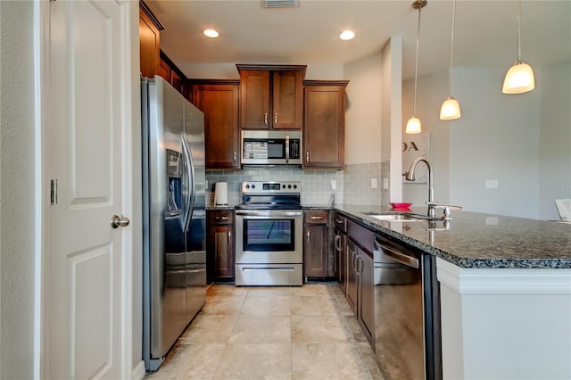 kitchen with stainless steel appliances, a peninsula, a sink, tasteful backsplash, and dark stone countertops