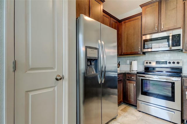 kitchen featuring light tile patterned floors, tasteful backsplash, dark stone counters, and stainless steel appliances