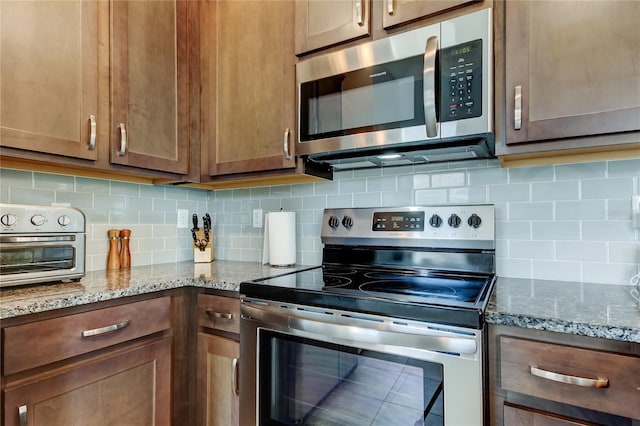 kitchen with stainless steel appliances, light stone counters, and decorative backsplash