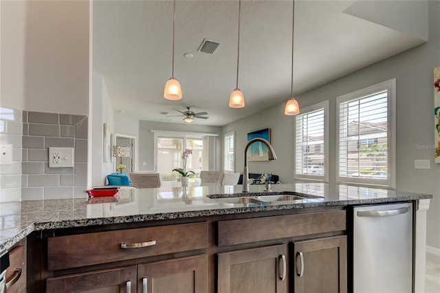 kitchen with a sink, a healthy amount of sunlight, stone countertops, and dishwasher