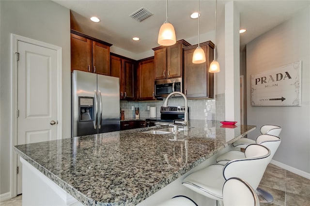 kitchen featuring visible vents, decorative backsplash, appliances with stainless steel finishes, dark stone countertops, and a peninsula