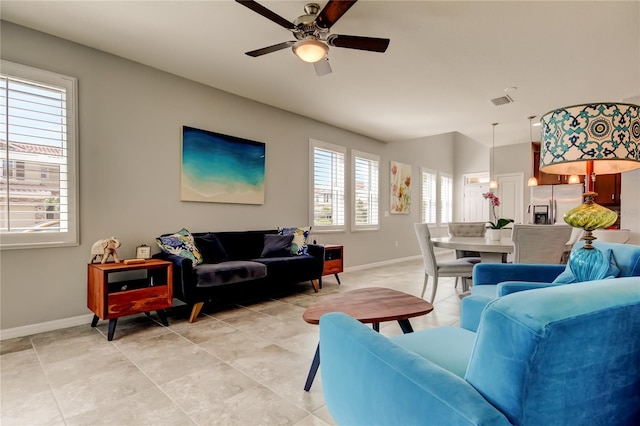 living room featuring light tile patterned floors, visible vents, baseboards, and a ceiling fan