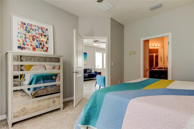 bedroom featuring baseboards, visible vents, ensuite bathroom, and light colored carpet