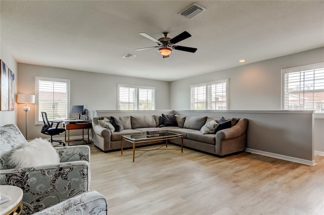 living area with light wood-type flooring, visible vents, and baseboards