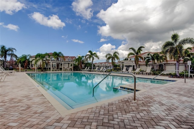 pool with a patio, fence, and a residential view