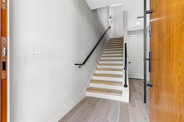 stairs with a barn door, baseboards, and wood finished floors