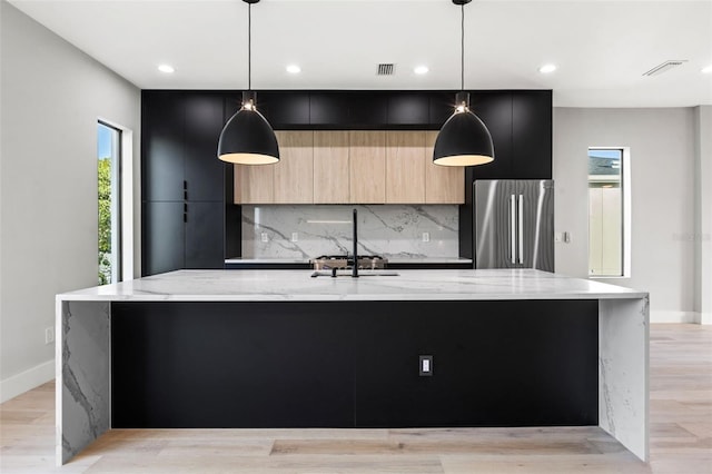 kitchen featuring a spacious island, visible vents, freestanding refrigerator, light brown cabinetry, and modern cabinets