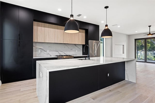 kitchen featuring visible vents, freestanding refrigerator, a sink, modern cabinets, and dark cabinetry