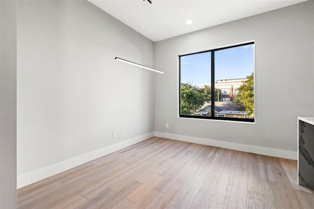 spare room featuring light wood-style floors, baseboards, and recessed lighting