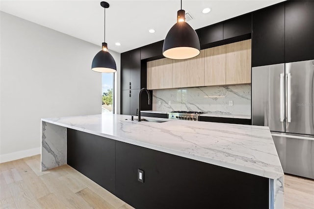 kitchen featuring modern cabinets, freestanding refrigerator, a large island with sink, dark cabinetry, and a sink